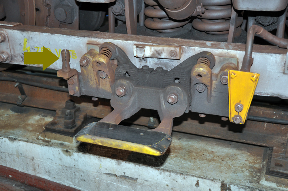 Sběrač napětí na podvozku vozu metra; na čudlík označený šipkou se připojuje pomocný kabel při výjezdu soupravy z depa - viz dále